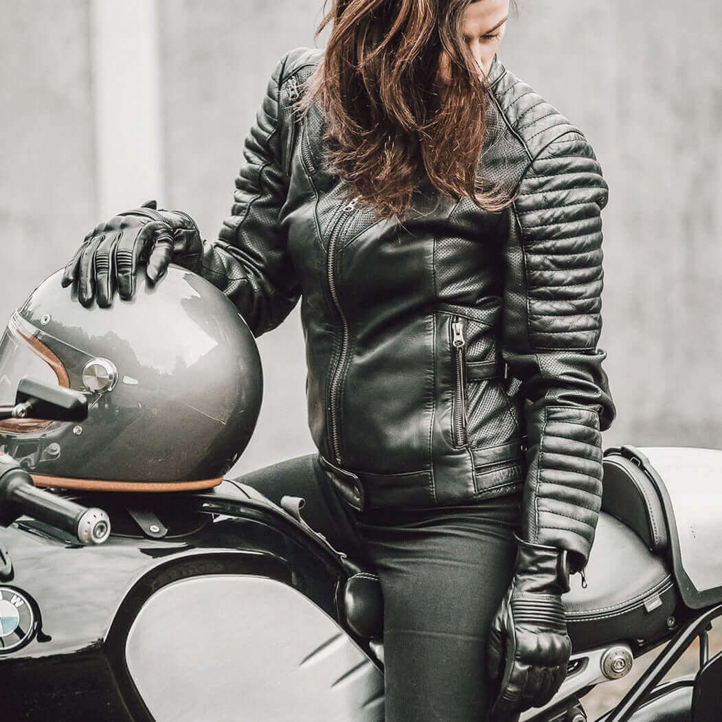 A woman sitting on a motorcycle wearing a black Wild and Free leather jacket