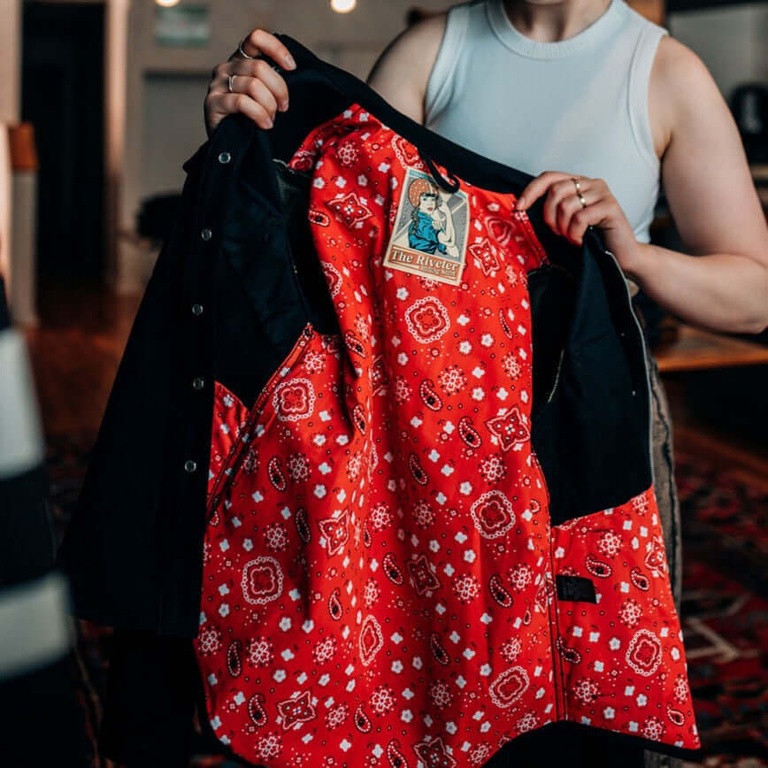 A woman showing the red bandana lining of a Tobacco Riveter Riding Shirt for motorcycle riding