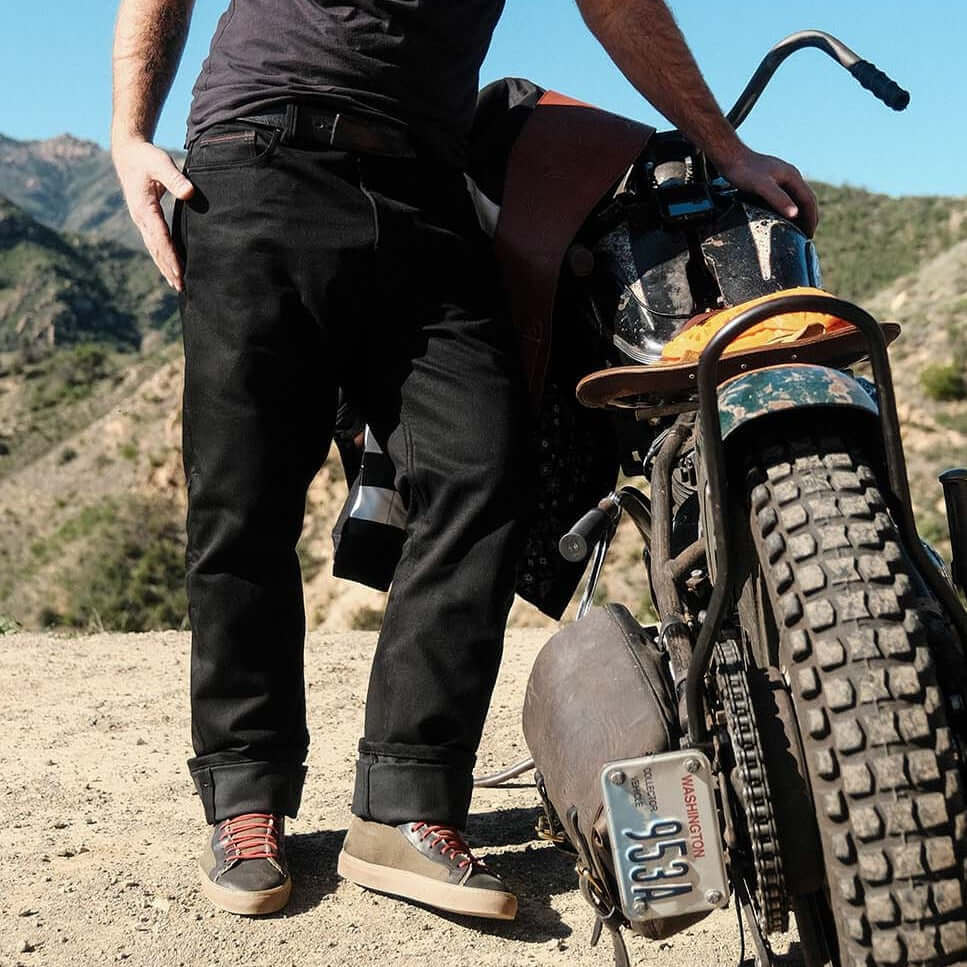 Tobacco Motorwear Ironsides Black Armored Jeans on male model leaning on dirty classic motorcycle