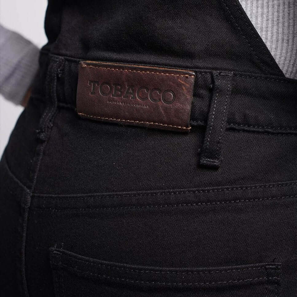 A close up of the leather label on the rear waist on Tobacco Boondocks overalls for women 