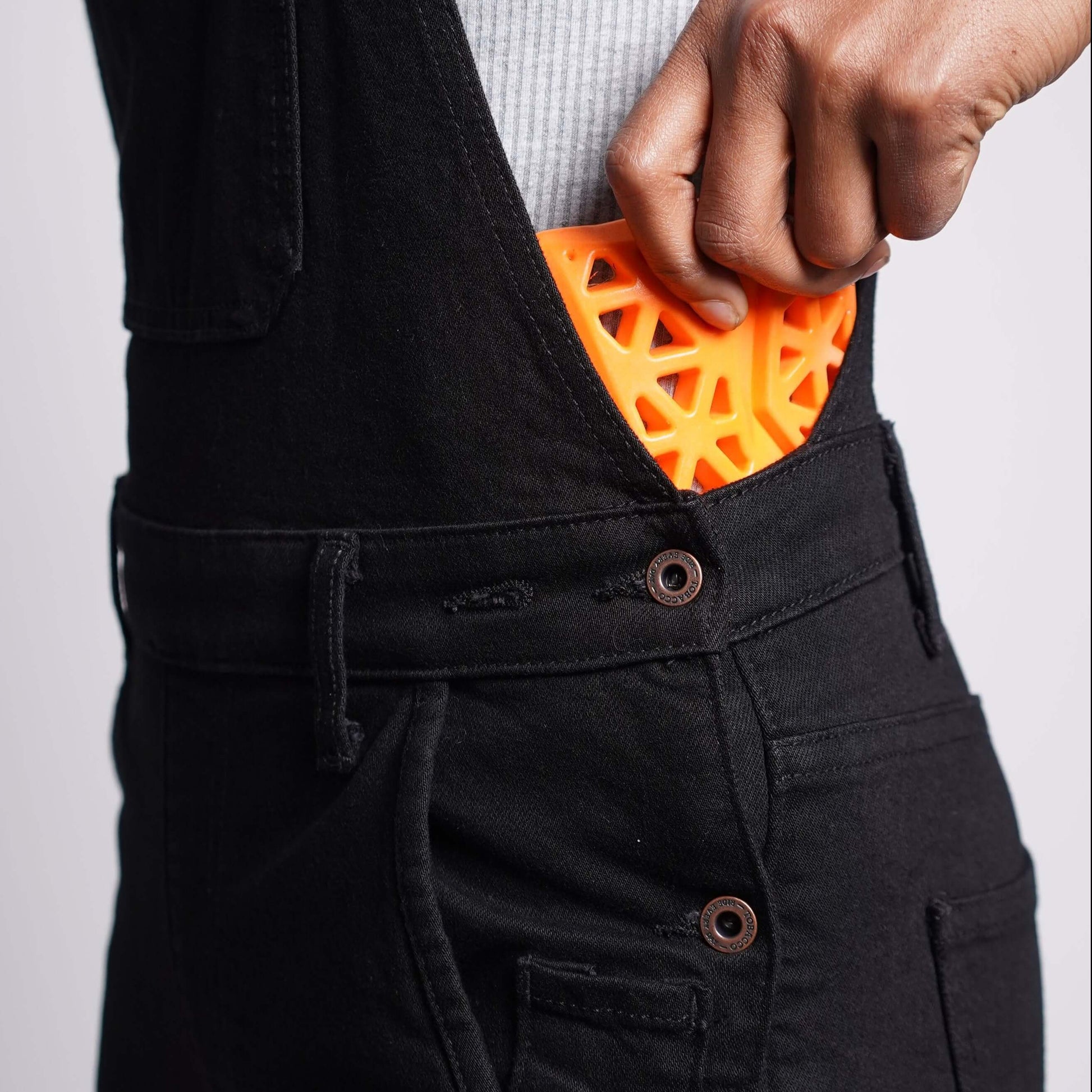 A side view of a woman sliding hip armor into her Boondocks motorcycle riding overalls