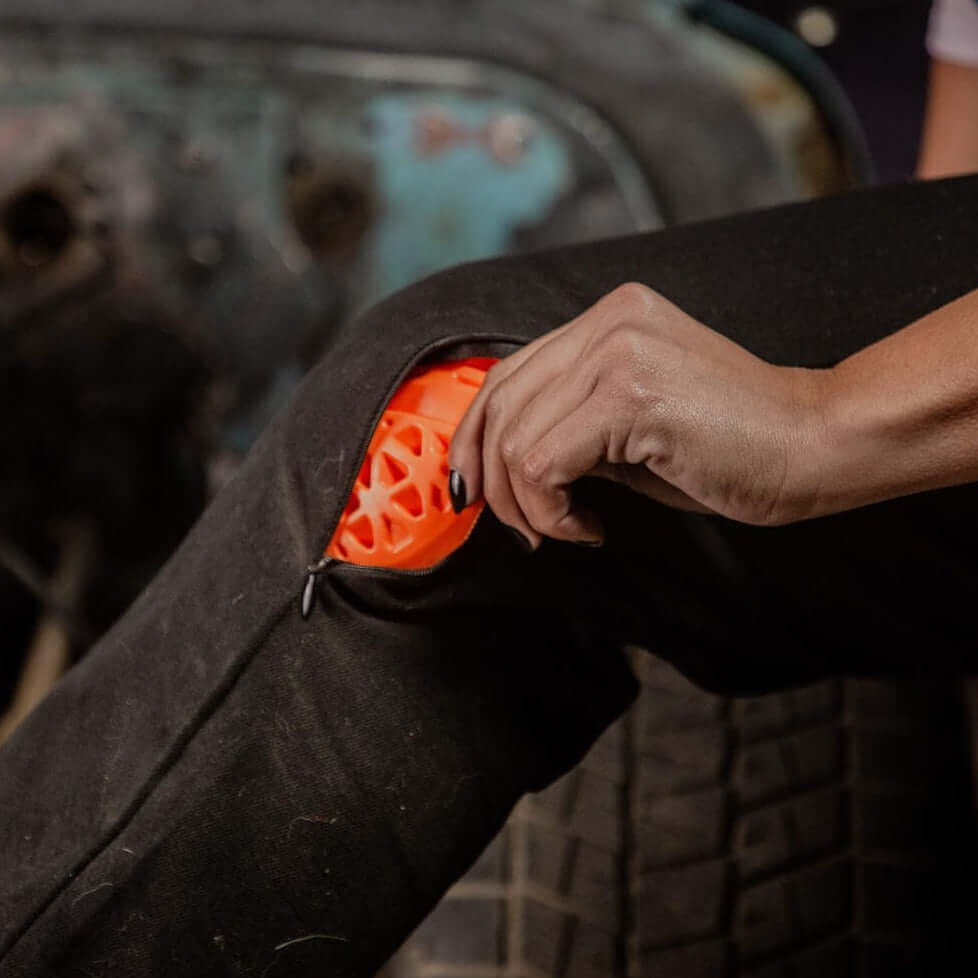 A woman's hand pulling knee armor out of the zippered knee pocket on Boondocks overalls