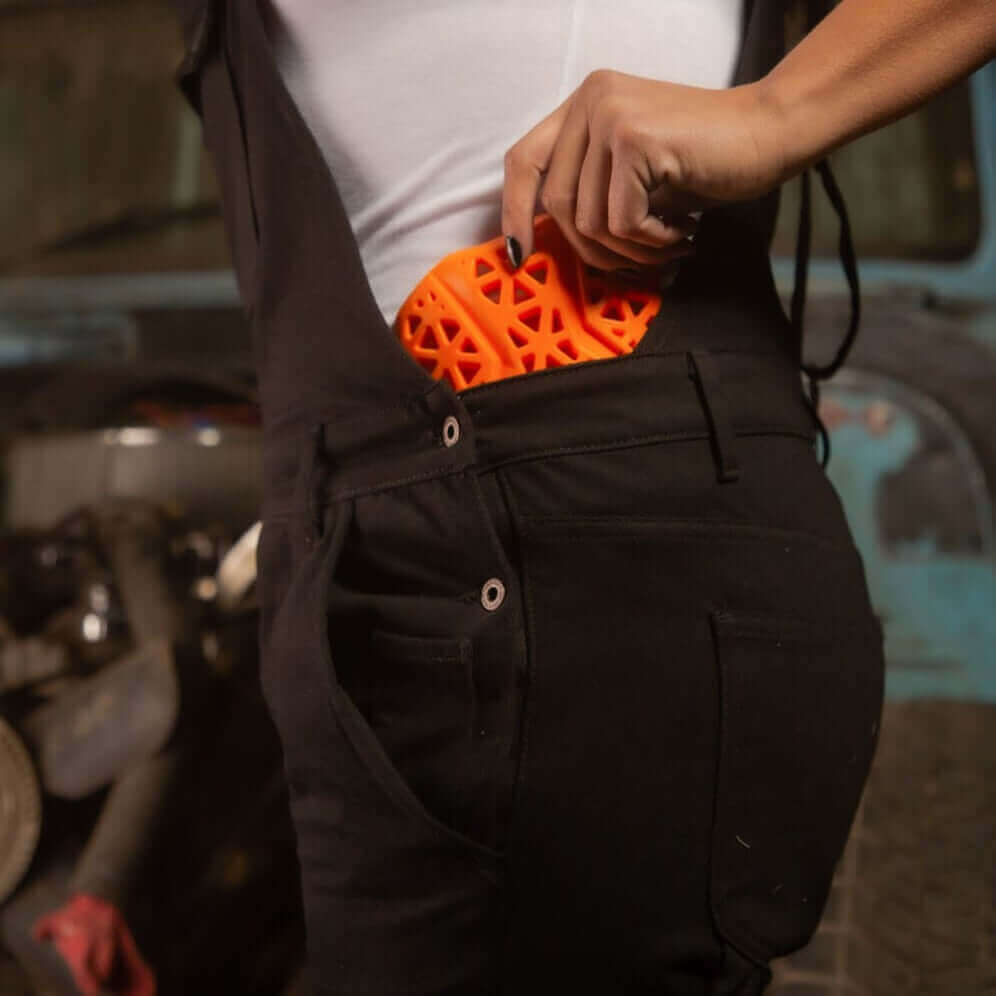 A side view of a woman inserting hip armor into her Boondocks overalls for motorcycle riding